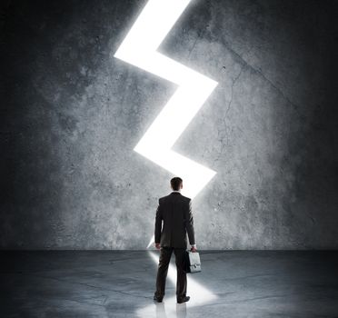 Businessman with briefcase standing in light of lightning sign