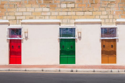 Neutral color of the facade of the house with colorful bright door. Building on the promenade of the fishing village Marsaxlokk, island Malta, Europe.