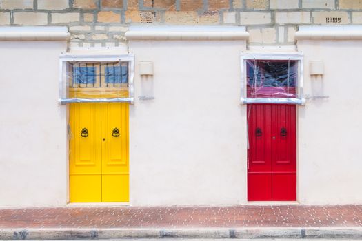 Neutral color of the facade of the house with colorful bright door. Building on the promenade of the fishing village Marsaxlokk, island Malta, Europe.