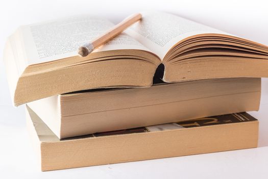 Stack of old books and pencil on withe background.