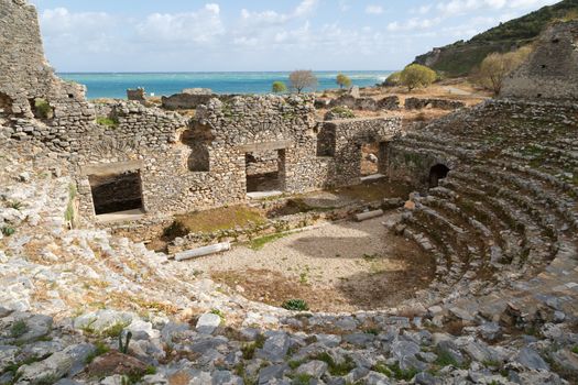 View of historical old amphitheater in Anemurium ancient city in Mersin, on cloudy blue sky background.