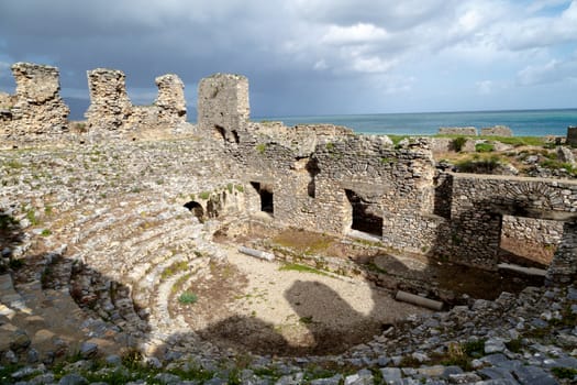 View of historical old amphitheater in Anemurium ancient city in Mersin, on cloudy blue sky background.