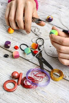 Hands with pair of pliers in the process of making jewelry from beads