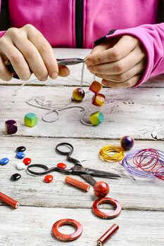 Hands with pair of pliers in the process of making jewelry from beads