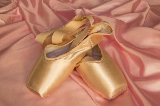 Ballet shoes on delicate pink silk background