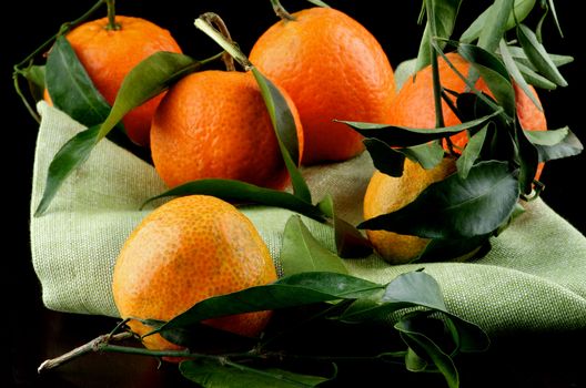 Arrangement of Ripe Tangerines with Leafs on Green Napkin closeup on Dark Wooden background