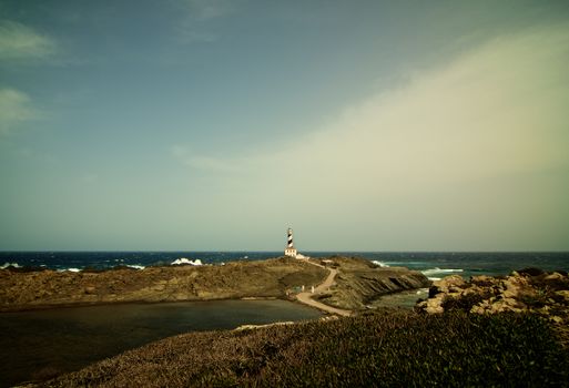 Lighthouse Cap de Favatrix on Stormy Sea Waves background Still Life. Northern Coast  of Menorca, Balearic Islands