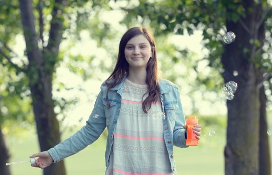 Young girl play with soap-bubbles in forest