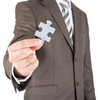 Businessman holding blank puzzle piece towards you isolated on white background