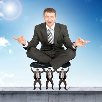 Young businessman sitting in lotus posture on little men
