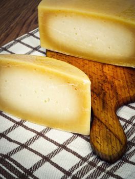 detail on round slicing cheese resting on wooden board