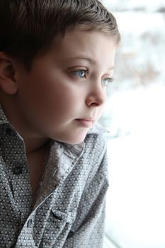 Young boy looking out of the window on a winters day