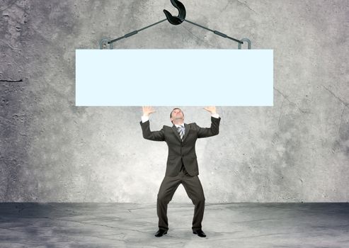 Businessman holding piece of blank wall, looking up