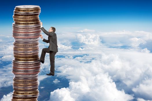 Businessman climbing up a huge stack of coins with sky background