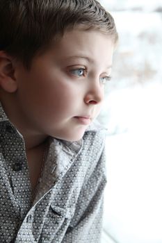 Young boy looking out of the window on a winters day
