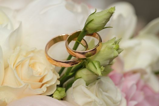 a bridal bouquet of roses with wedding rings lying on it