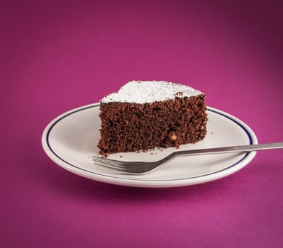 CLoseup of slice of chocolate cake  on colored background