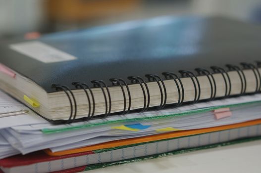 Stack of report and black notebook placed on desk at office.