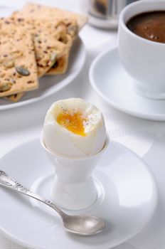 Soft-boiled egg with cup of coffee and crackers for breakfast