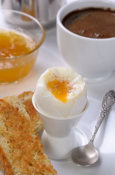 Soft-boiled egg with cup of coffee, toast and jam for breakfast