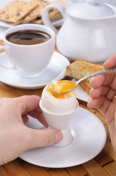 A cup of coffee with a soft-boiled egg and toast for breakfast