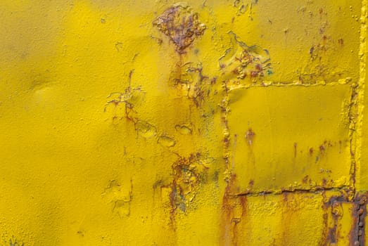 fragment of an iron surface is covered with yellow color paint, which has long been under the influence of different climatic conditions