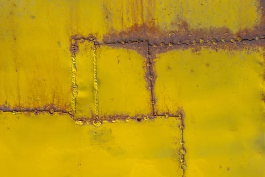 fragment of an iron surface is covered with yellow color paint, which has long been under the influence of different climatic conditions