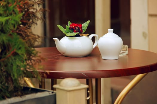summer cafe white cup and teapot, tea, wooden table outdoors at the phono flowers, Europe, leisure, tourism, catering