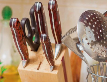 kitchen utensils kitchen knives, wooden and metal ladles and skimmers in a kitchen interior