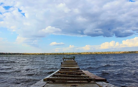 wooden pontoon bridge across the water, the river ponds, summer weather, blue sky and clouds