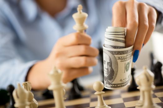 Business persons holding dollars above the chessboard