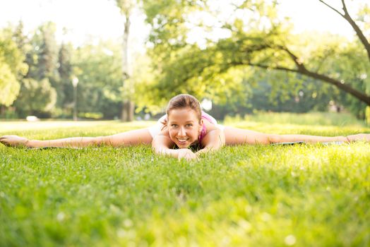 Beautiful young woman doing relaxing and stretching exercises in the park.