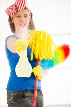 Portrait of a smiling young beautiful maid holding a cleaning equipment and looking at camera. 