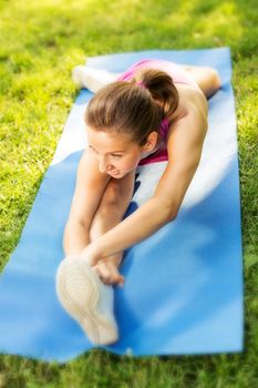Cute young woman doing stretching exercises in the park. Selective Focus.