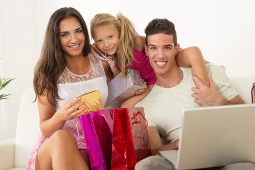 Beautiful happy family sitting at home with laptop and shopping bags.