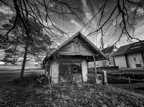 Small cottage surrounded with trees in the coutryside in black and white