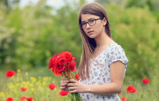 Portrait of young girl with poppy flowers in nature