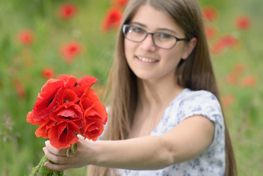 Young girl with poppy bouquet on field