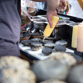 Chef making  burgers outdoor on open kitchen international food festival event. Street food ready to serve on a food stall.