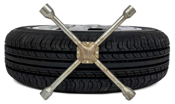 Car tyre with screwdriver on white background