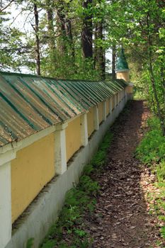 Nice yellow ancient stone wall and path in summer forest