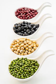 Set of beans, Soy or yellow bean, Azuki or red bean, Mung bean and black bean in white spoon on white background.