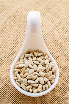 Fresh Sunflower Seeds in white spoon on sack background.