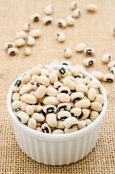 White bowl full of black-eyed peas on sack background.