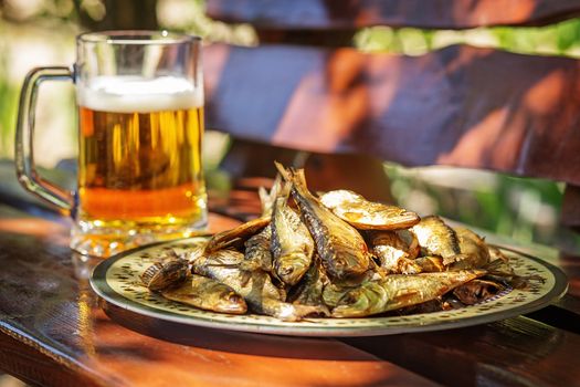 Tasty smoked herring lies on a plate and a glass of cold beer