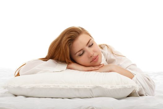 Young beautiful girl sleeps in the bed hugging a pillow on his stomach. Healthy sleep. Isolated on white background.