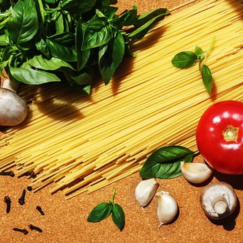 ingredients for cooking Italian pasta on a cork board