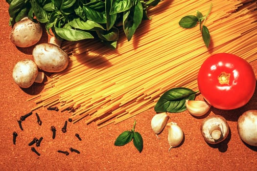 ingredients for cooking Italian pasta on a cork board
