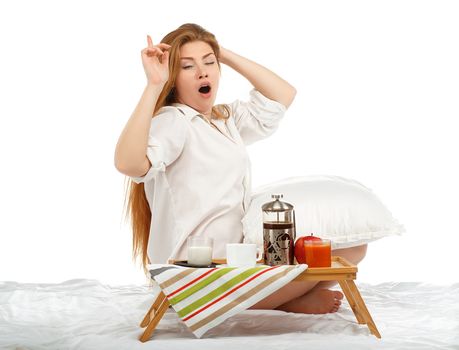 Beautiful young woman stretching in bed in the morning with breakfast tray isolated on white background. Good morning concept.