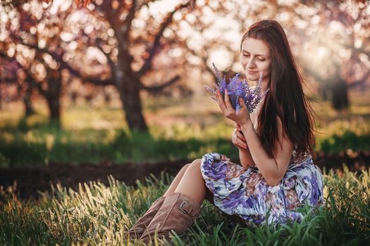 Portrait of a young beautiful girl with a bouquet of lavender in her hands in the spring garden